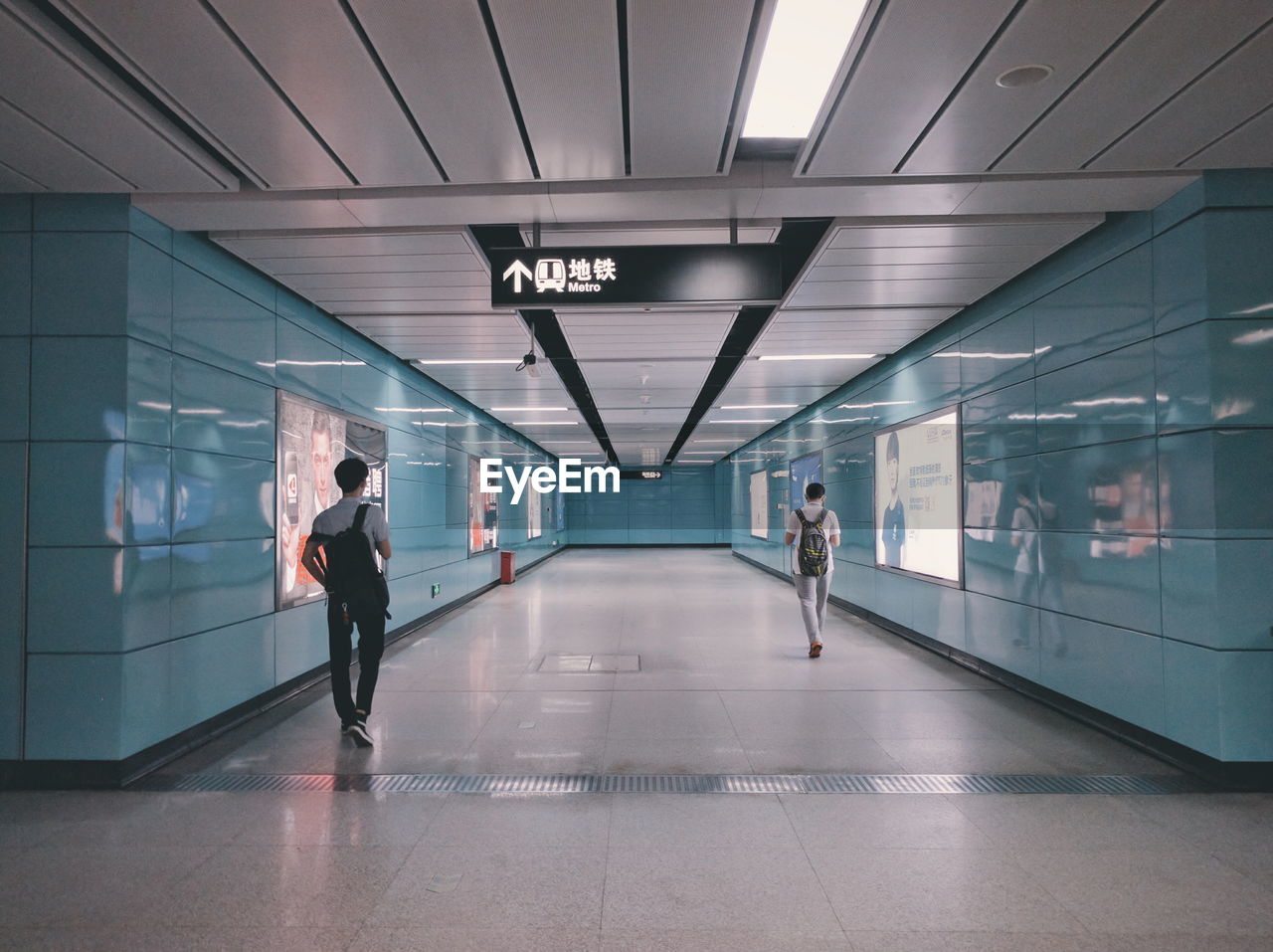 Rear view of men walking on walkway at subway station