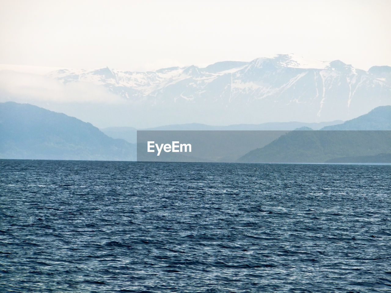 Scenic view of sea by mountains against clear sky