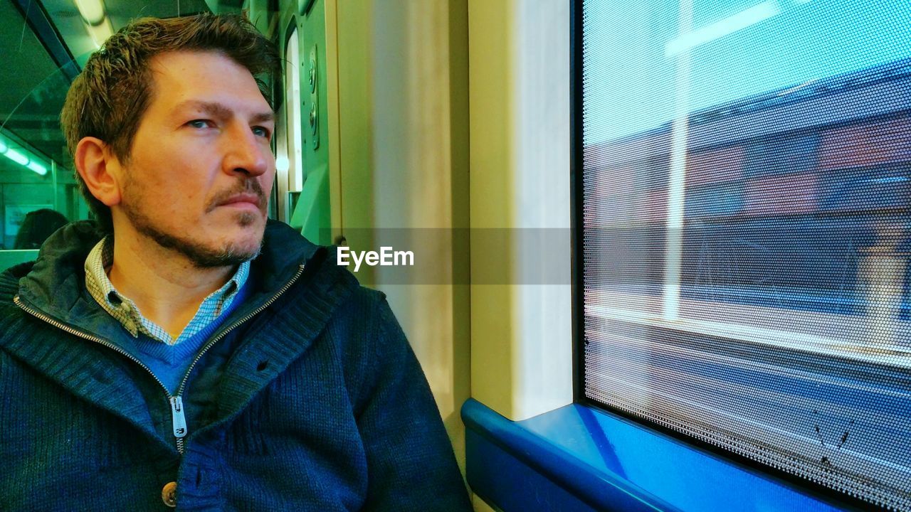 Man in warm clothing sitting by window in train