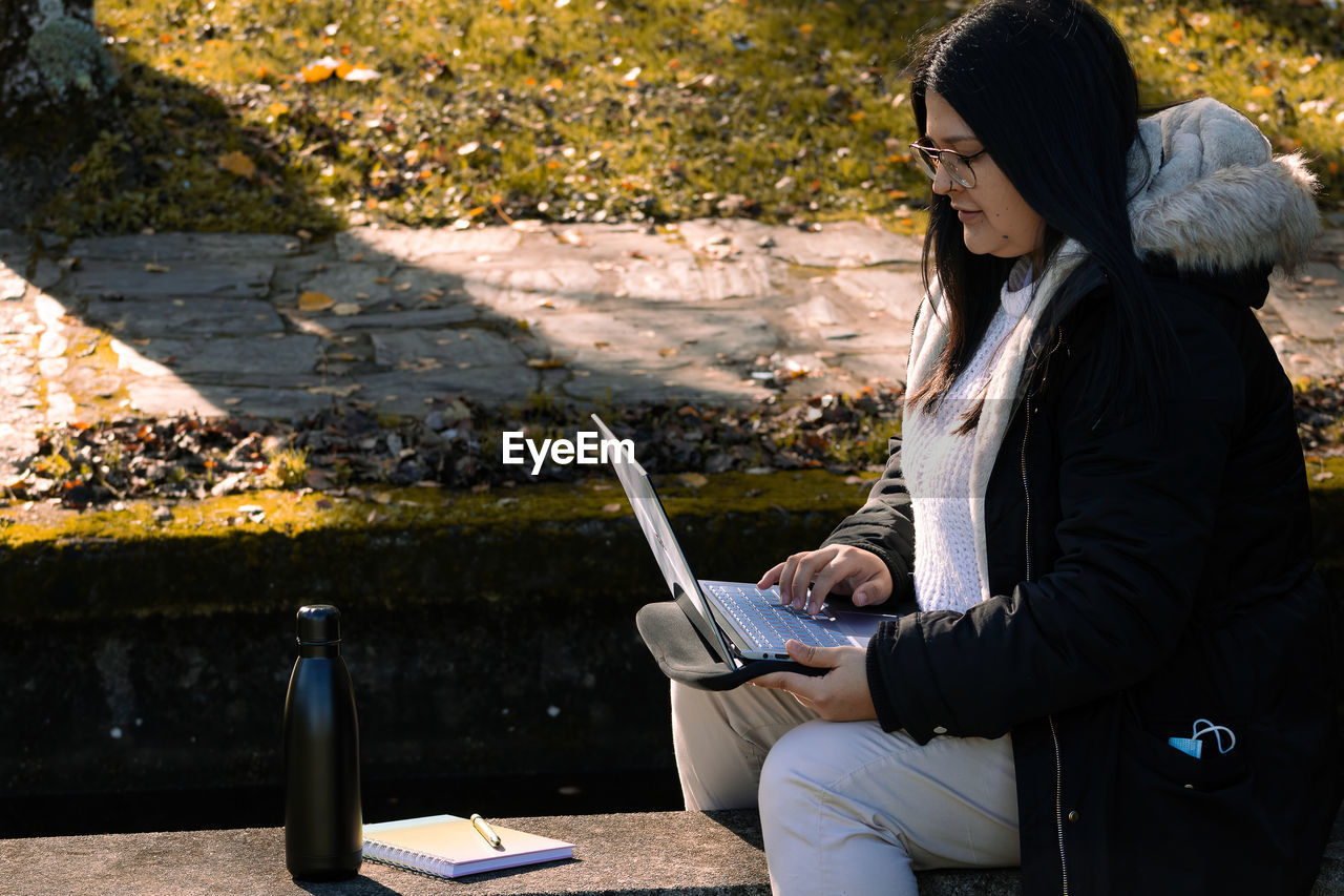 Woman working in the park with laptop. teleworking outdoors due to coronavirus. online business.