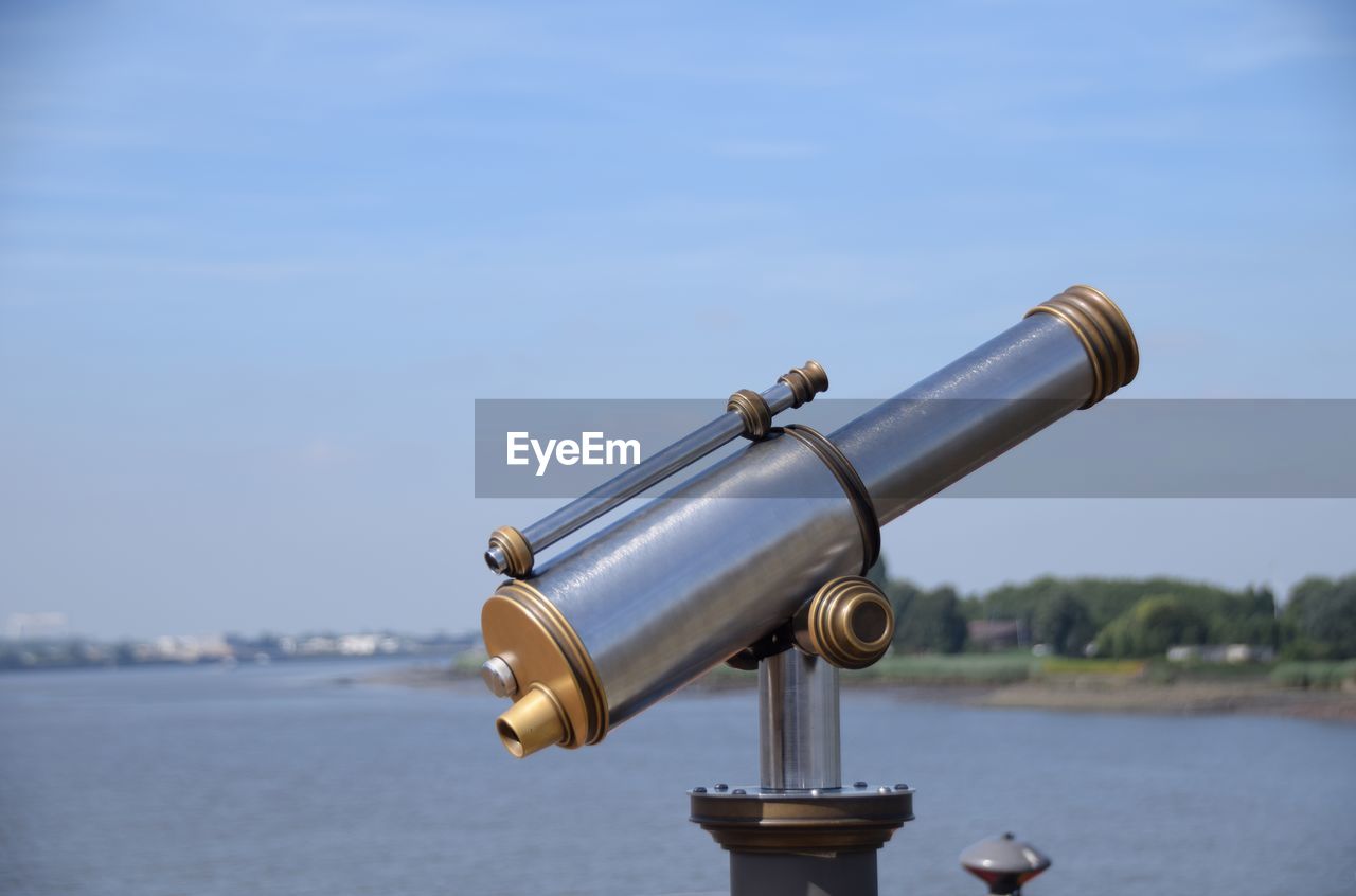 Close-up of coin-operated binoculars by sea against sky