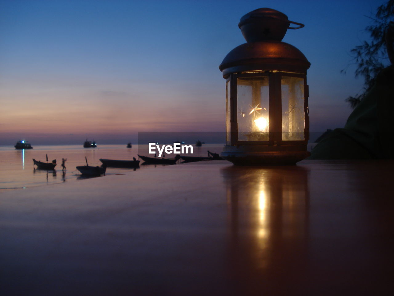 CLOSE-UP OF ILLUMINATED LAMP AT SUNSET