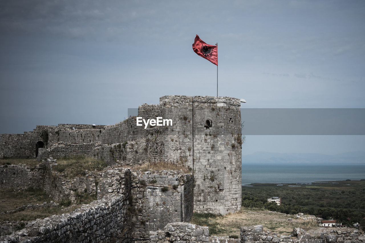 Low angle view of albanian flag on old ruin against sky