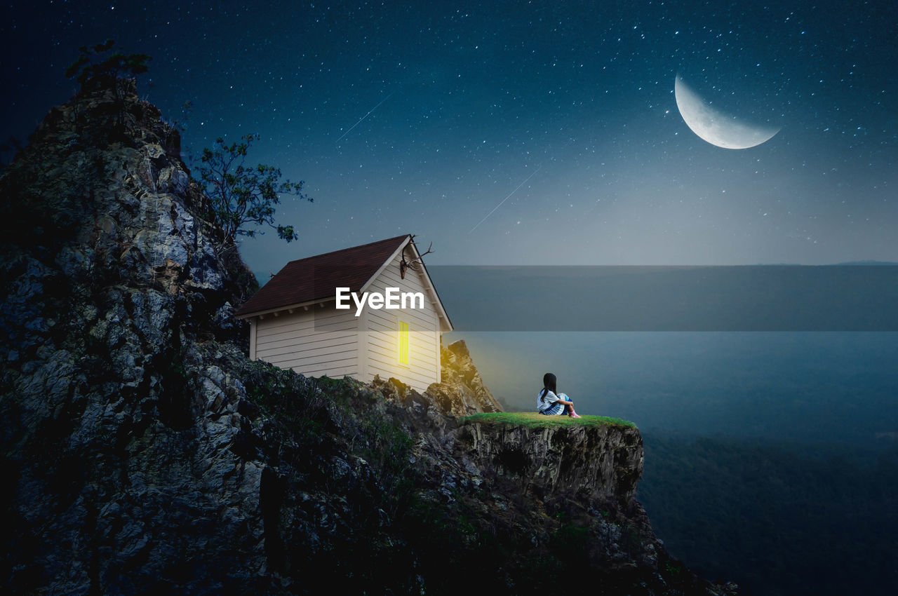 DIGITAL COMPOSITE IMAGE OF MAN AND MOON AT NIGHT