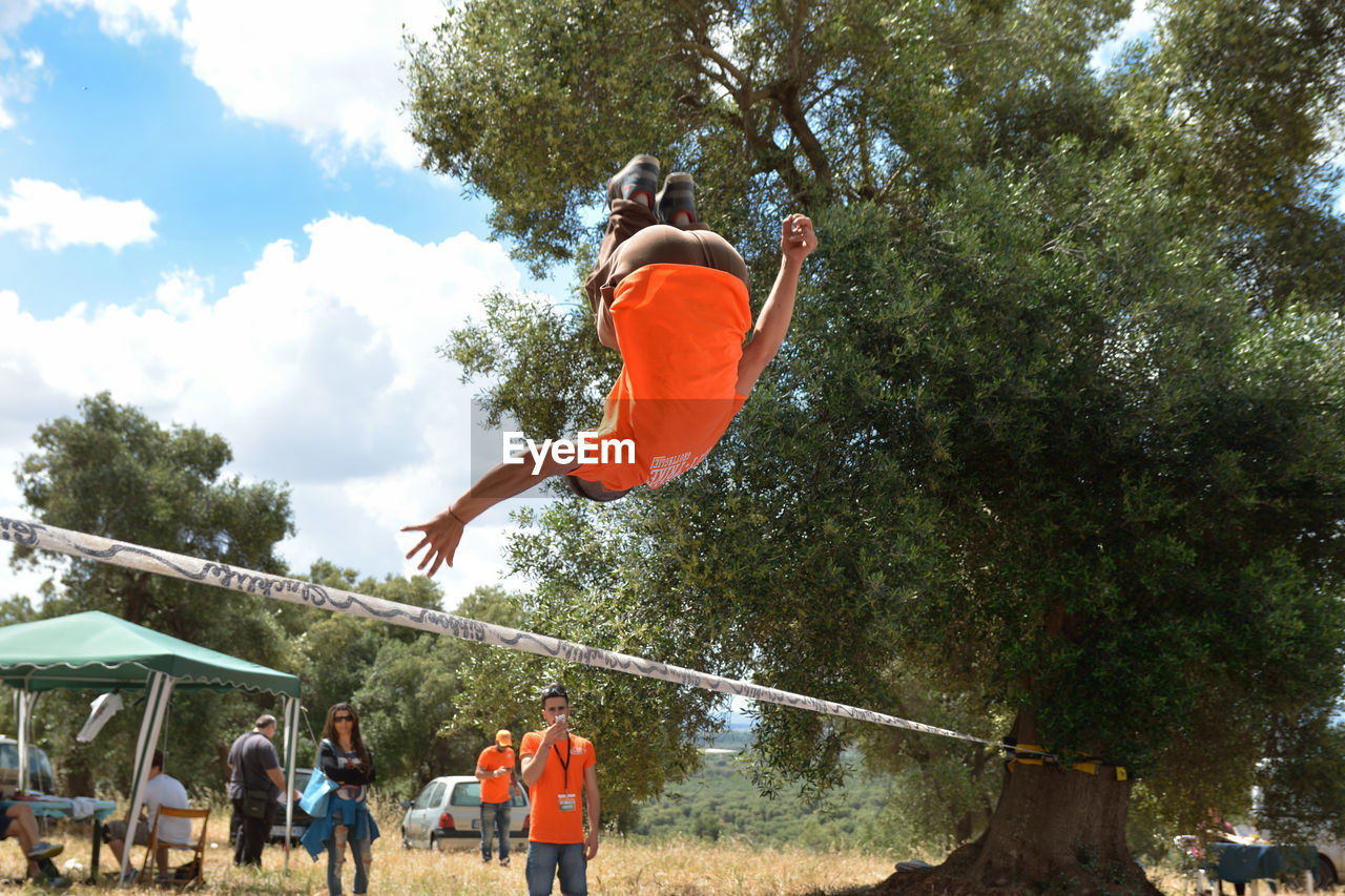 REAR VIEW OF MAN JUMPING IN PARK