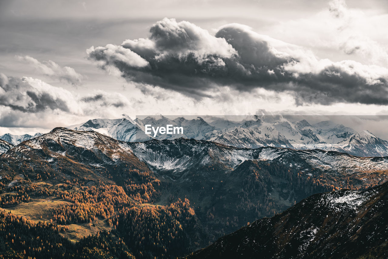 Dramatic sky over snow capped mountains in fall colors, saalbach, salzburg, austria.