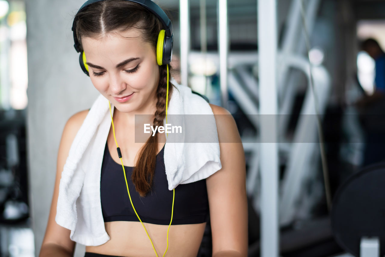 Woman listening music through headphones while sitting in gym