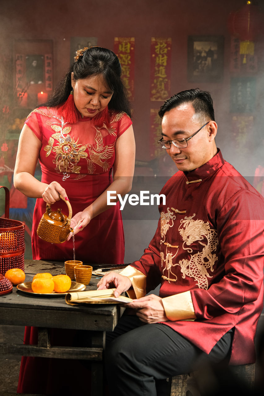 two people, adult, women, men, food and drink, togetherness, three quarter length, indoors, food, smiling, female, emotion, mature adult, sitting, happiness, clothing, lifestyles, holding, asian food, front view, person, healthy eating, young adult, table, wellbeing, bonding, eyeglasses, positive emotion