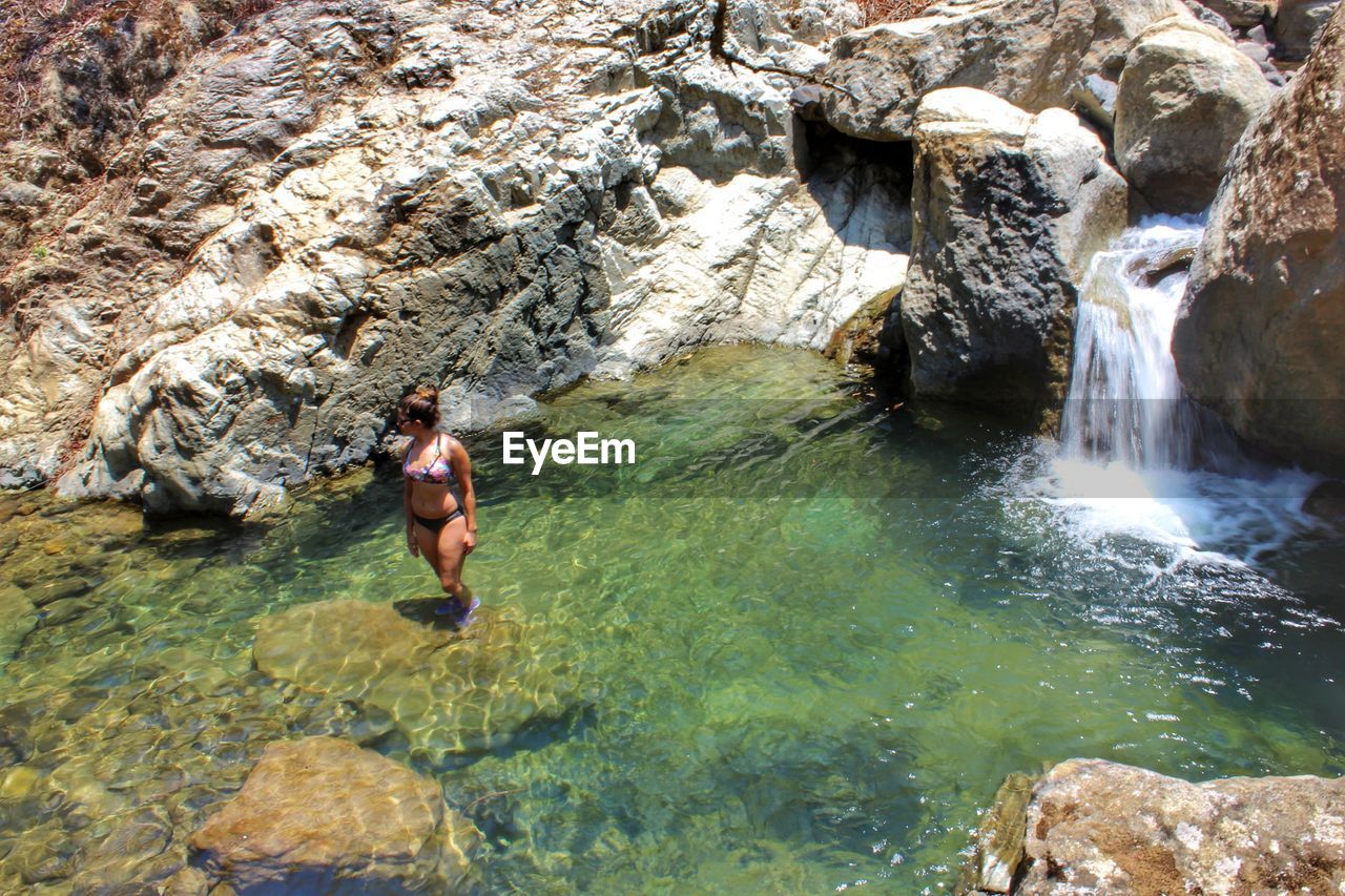 FULL LENGTH OF SHIRTLESS MAN STANDING ON ROCK