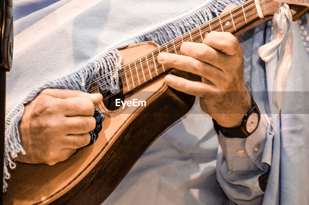 Midsection of man playing ukulele
