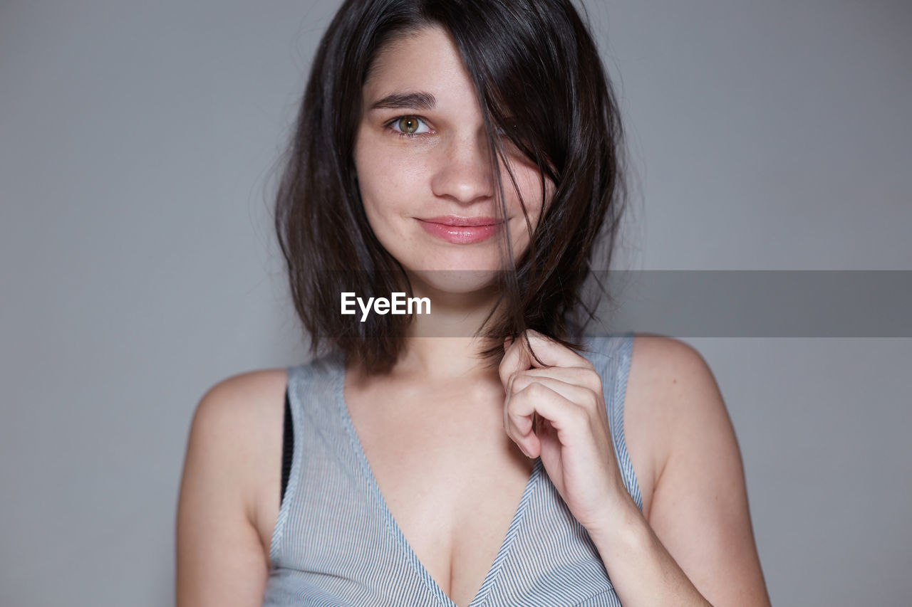 Portrait of smiling young woman over gray background