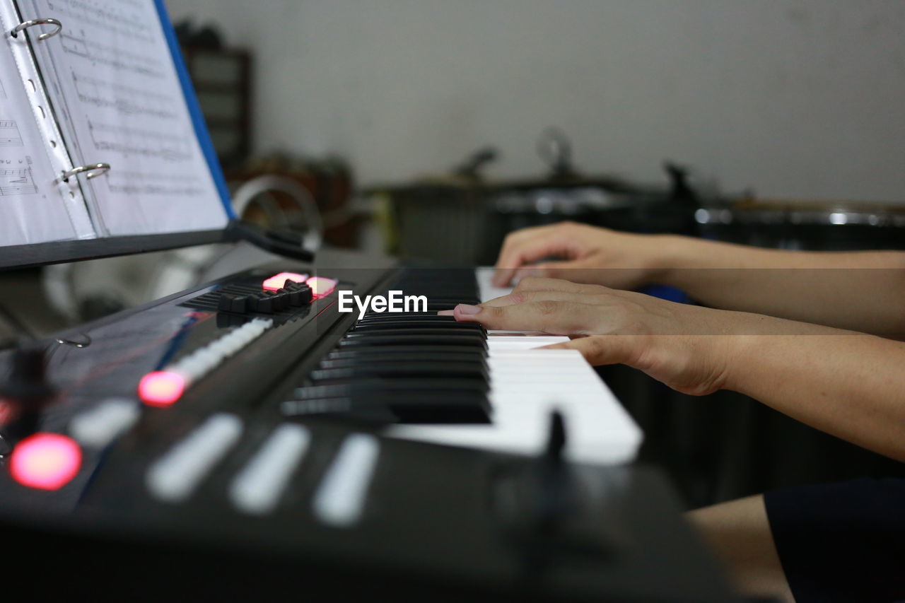 Cropped hands playing piano in recording studio