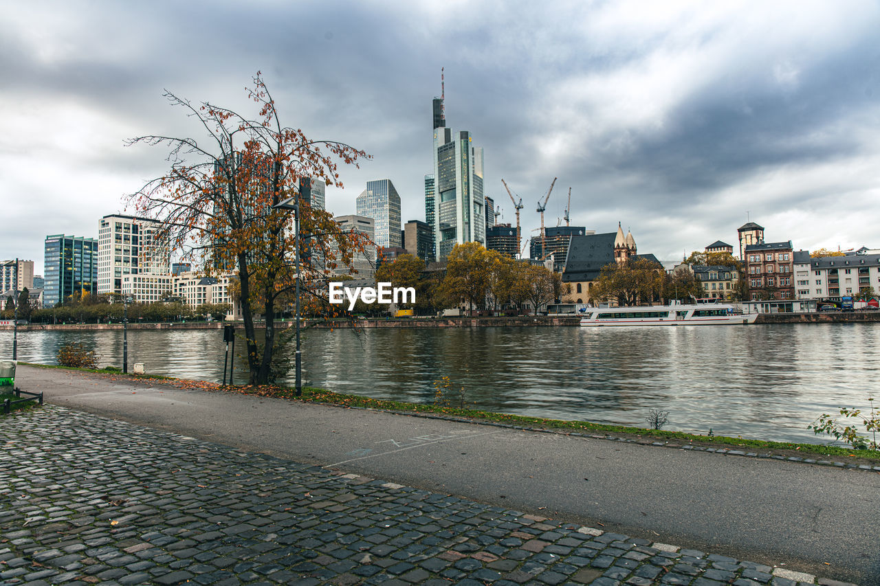 bridge over river in city against cloudy sky