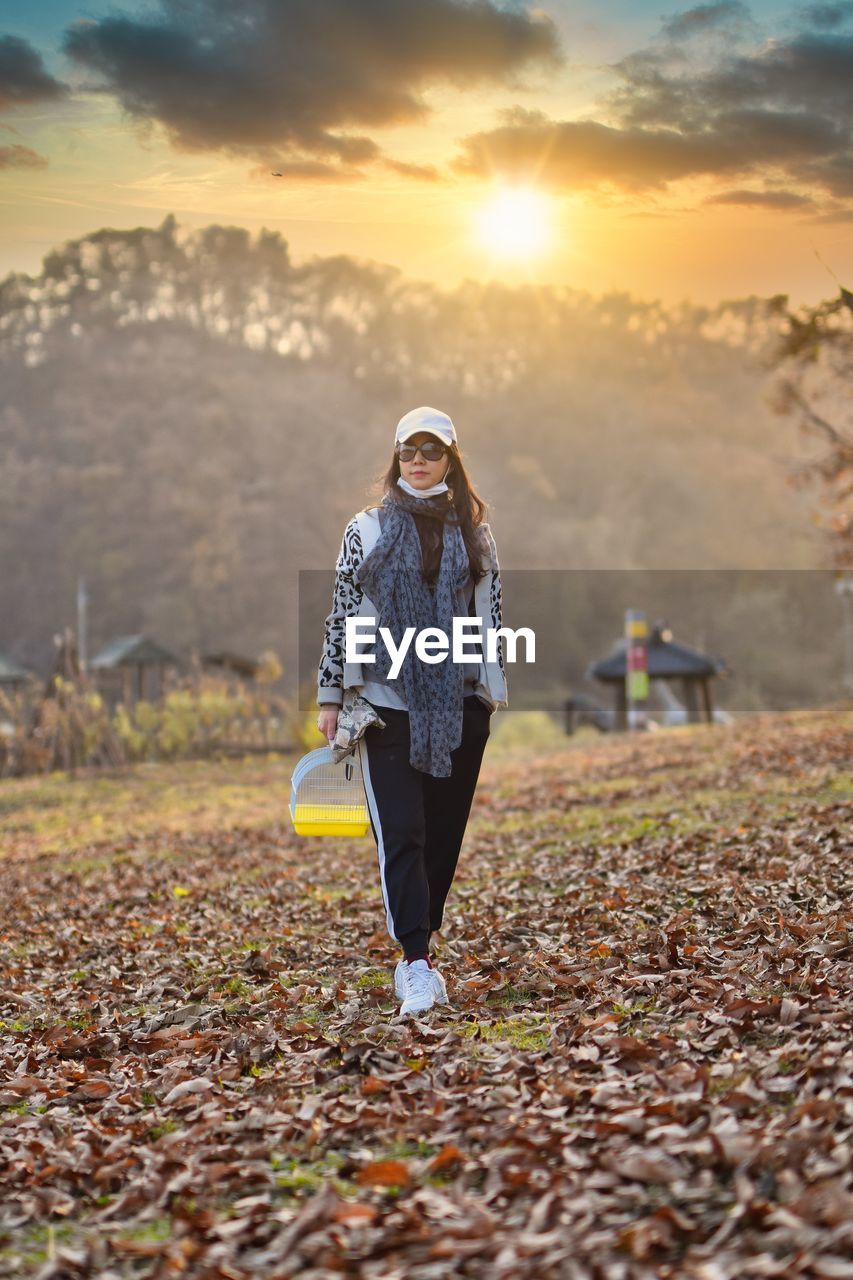 Full length of woman standing on field against sky