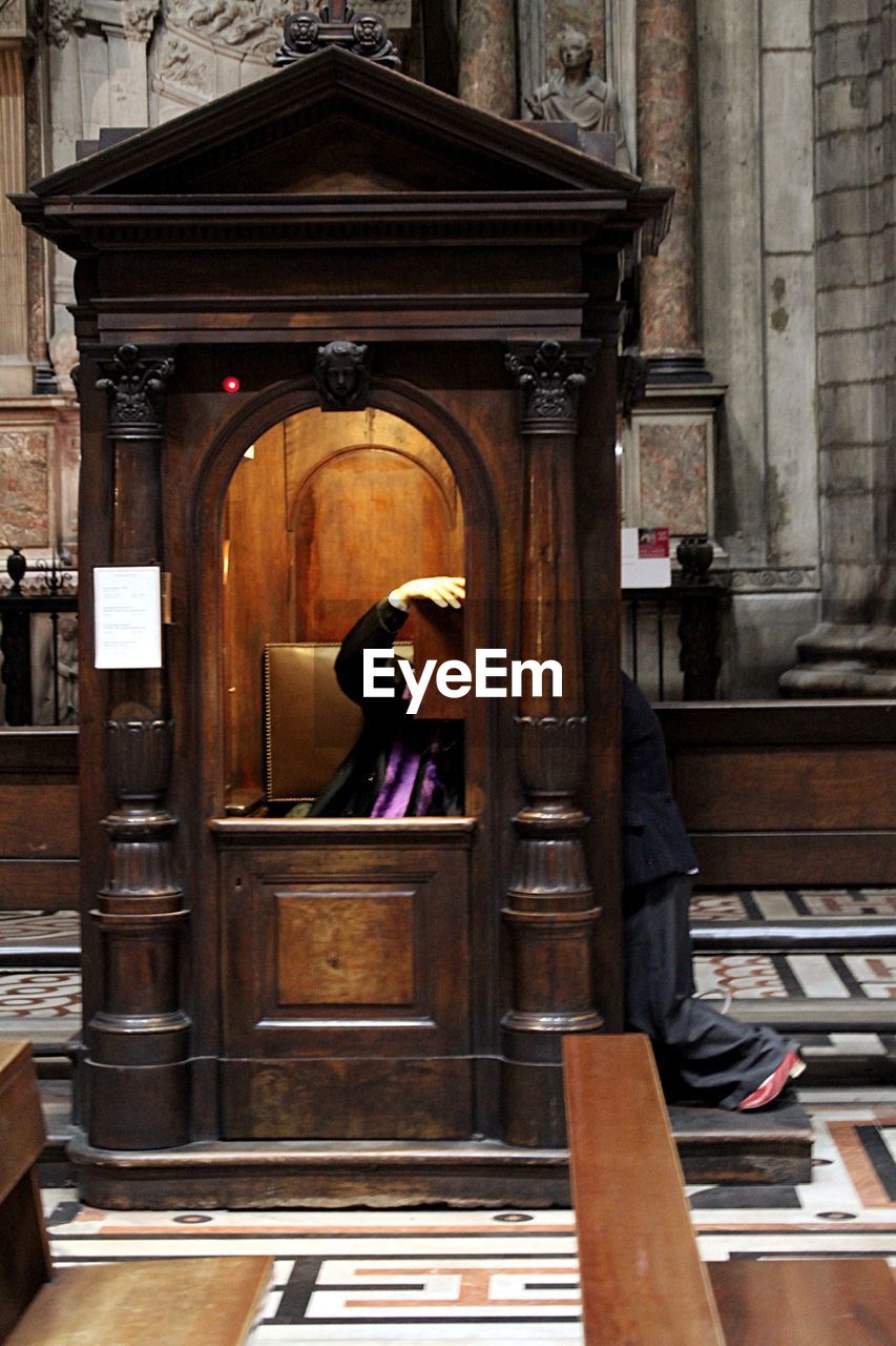 People under wooden hut inside church building