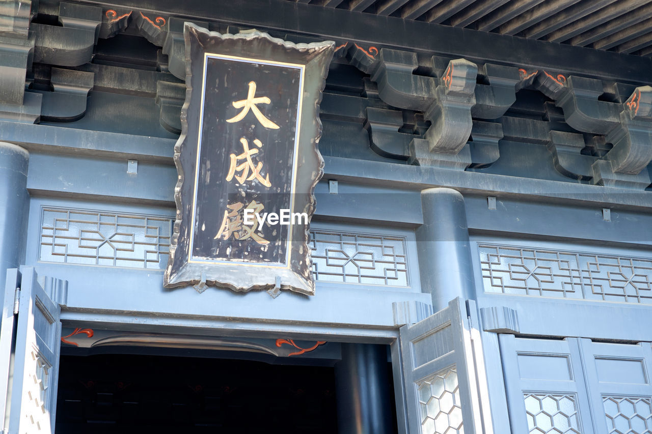 Low angle view of text on board above doorway at yushima seido
