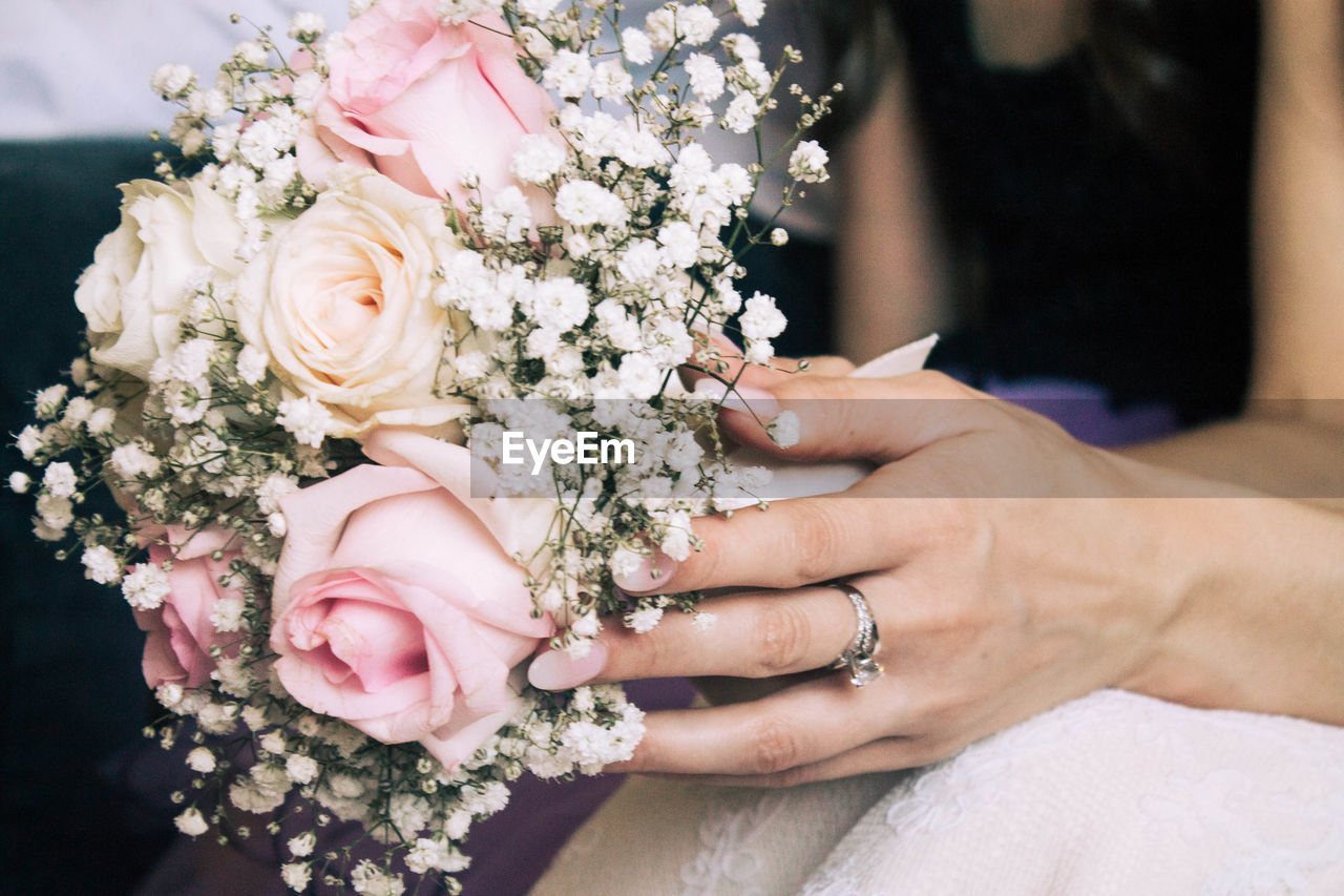 Midsection of bride holding bouquet