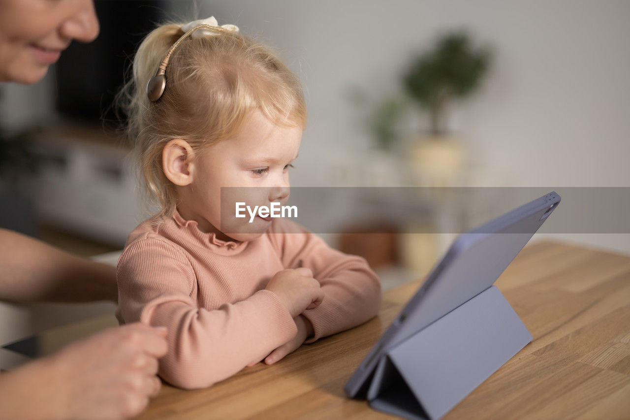 close-up of cute baby boy using digital tablet while sitting at home