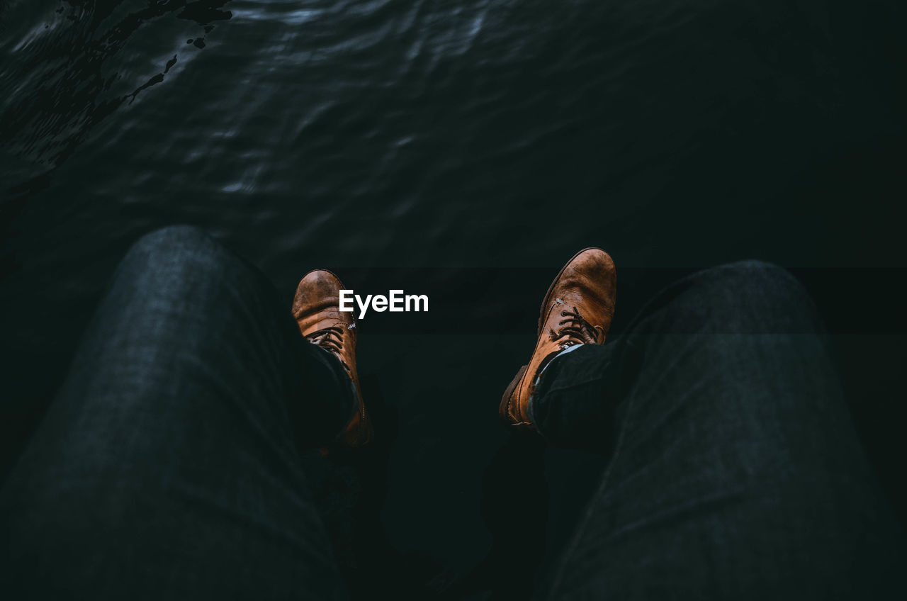 Low section of man sitting over lake