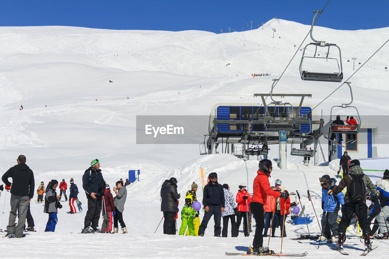 snow, cold temperature, mountain, skiing, winter, ski, ski equipment, sports, winter sports, group of people, nordic skiing, mountain range, nature, travel, sports equipment, piste, leisure activity, vacation, trip, day, travel destinations, ski touring, adventure, cable car, environment, holiday, men, ski mountaineering, ski holiday, adult, scenics - nature, landscape, large group of people, beauty in nature, crowd, clothing, sky, transportation, full length, downhill, ski lift, tourism, extreme sports, frozen, ski-wear, recreation, outdoors, land, ski resort, women, ice, lifestyles, white, non-urban scene