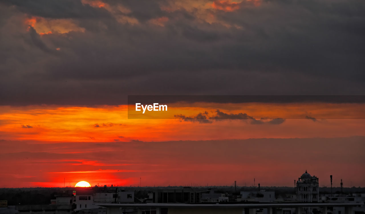 VIEW OF BUILDINGS AGAINST DRAMATIC SKY DURING SUNSET