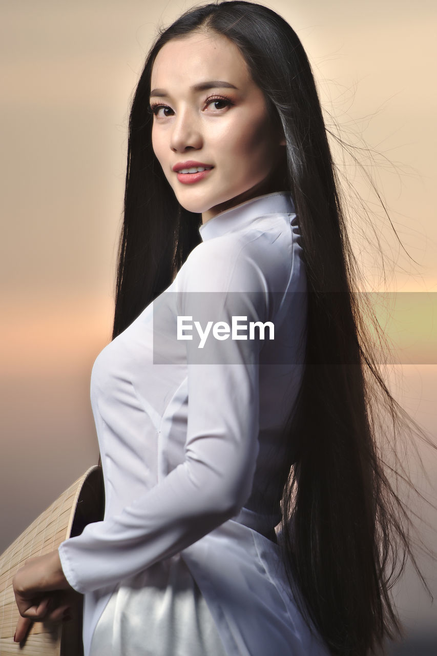 Portrait of beautiful asian girls with ao dai vietnam traditional dress on sunset landscapes.