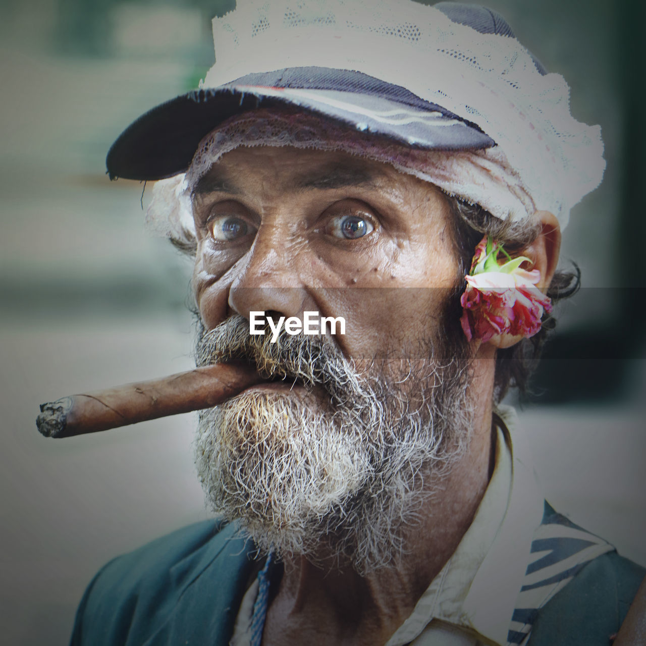 Portrait of senior man in cap smoking cigar