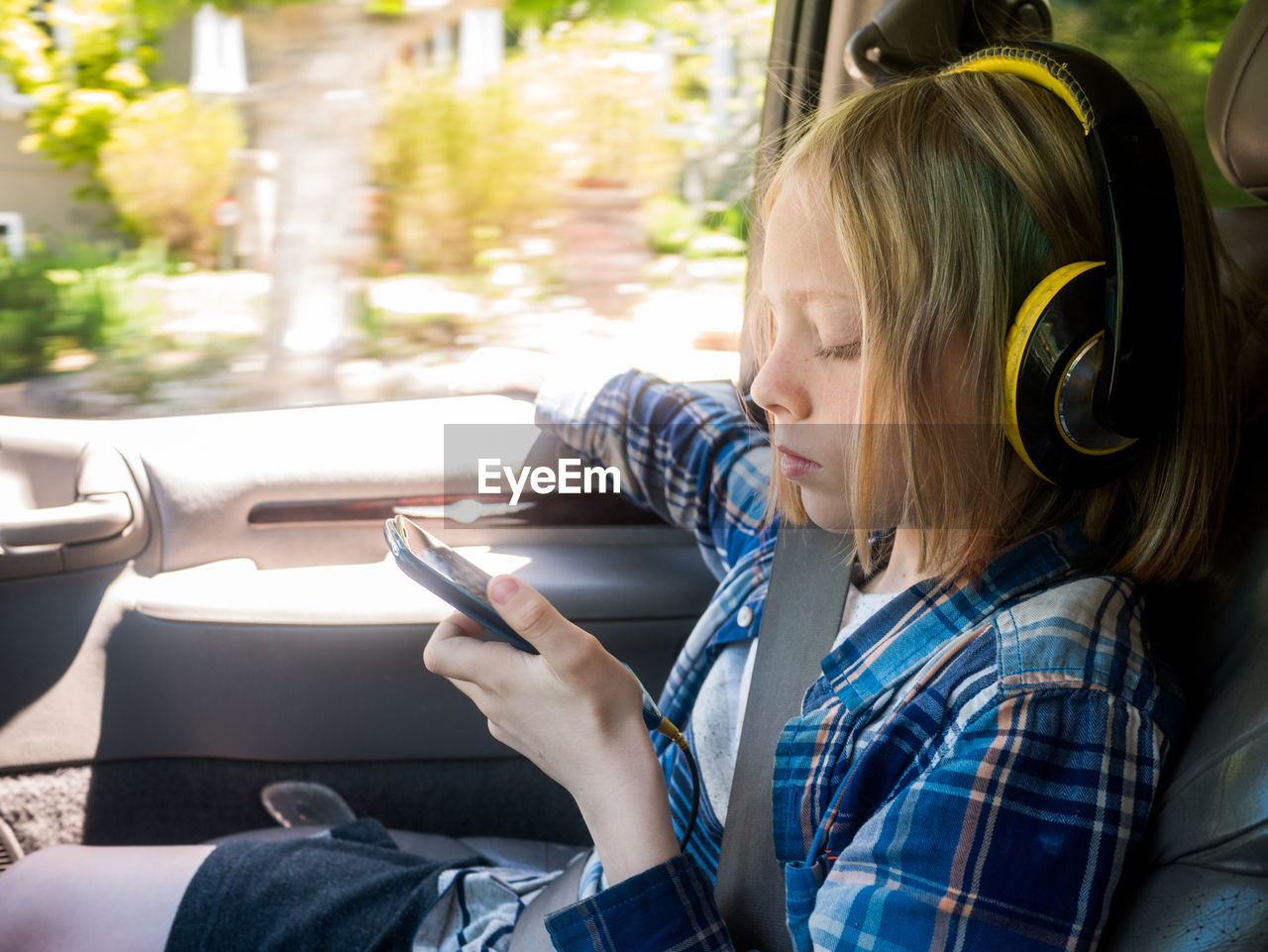 Boy looking at mobile phone while listening music in car