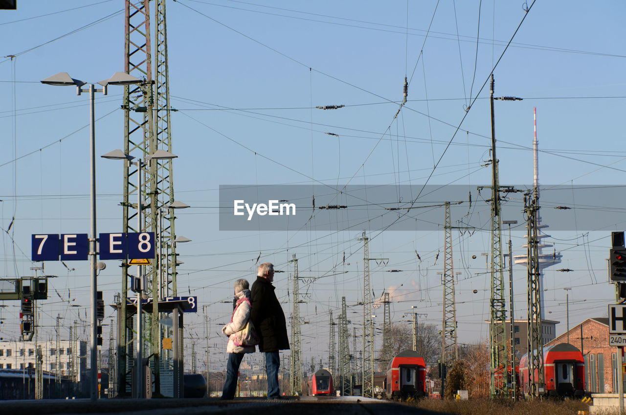 MAN STANDING ON ELECTRICITY PYLON