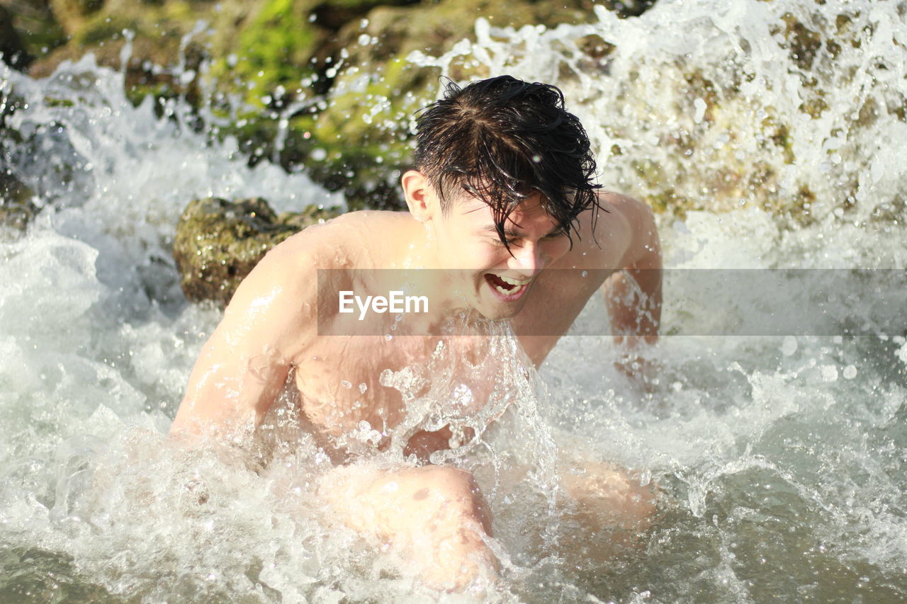 Close-up of shirtless man splashing water in lake