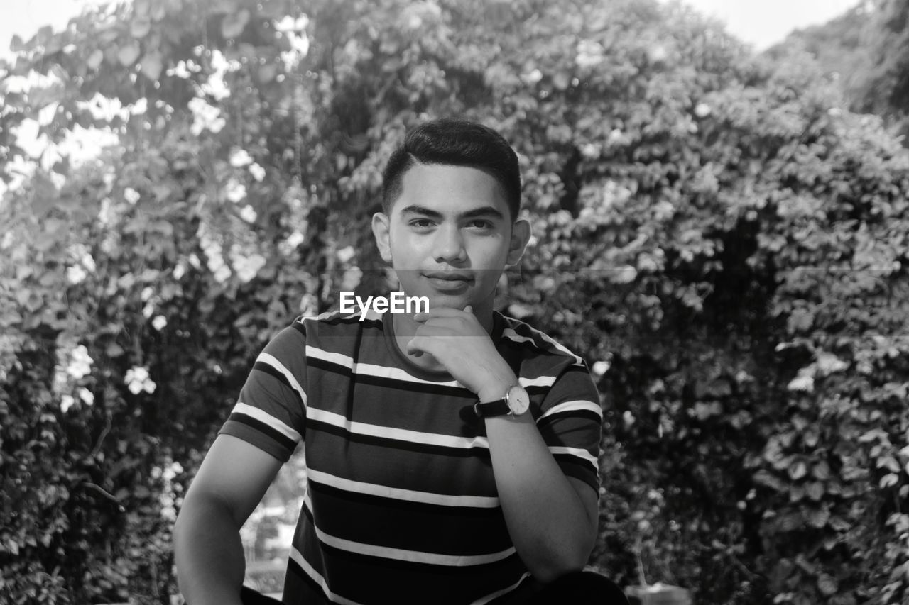 Portrait of young man against trees