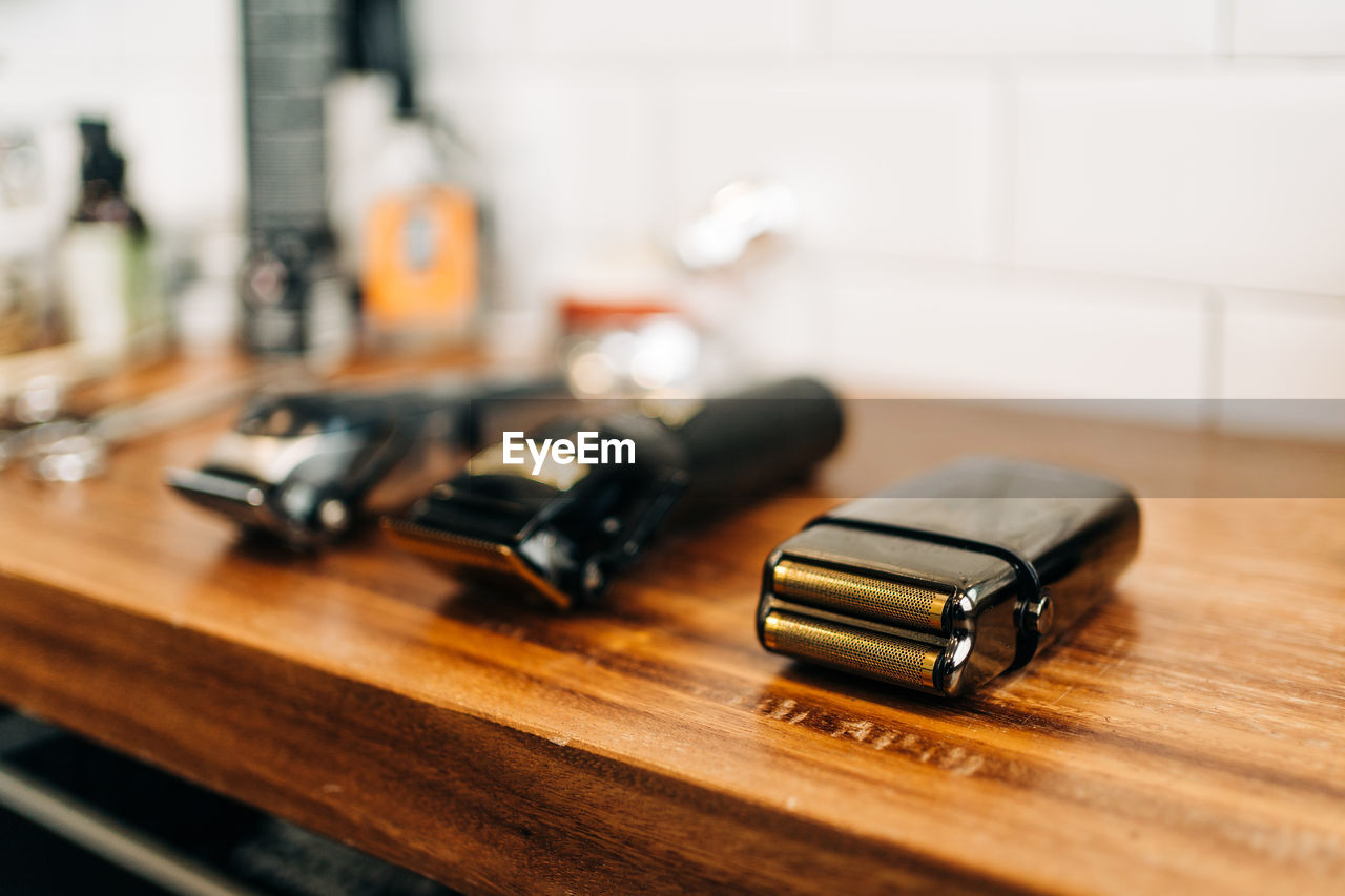 Collection of professional electric clippers near bottles of cosmetic products and washbasin in bathroom of barbershop