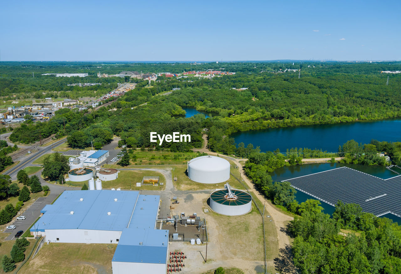 HIGH ANGLE VIEW OF SWIMMING POOL BY TREES AGAINST SKY