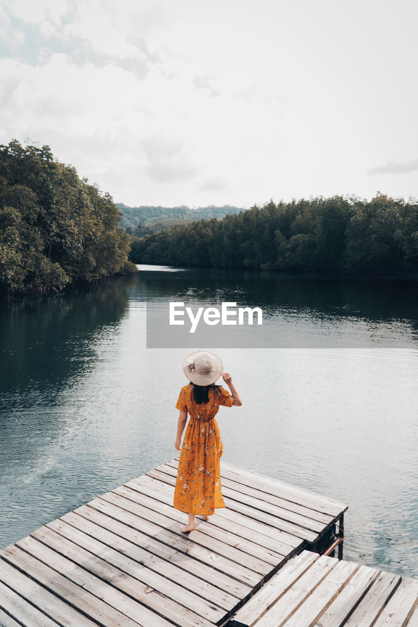 FULL LENGTH OF WOMAN STANDING ON PIER OVER LAKE