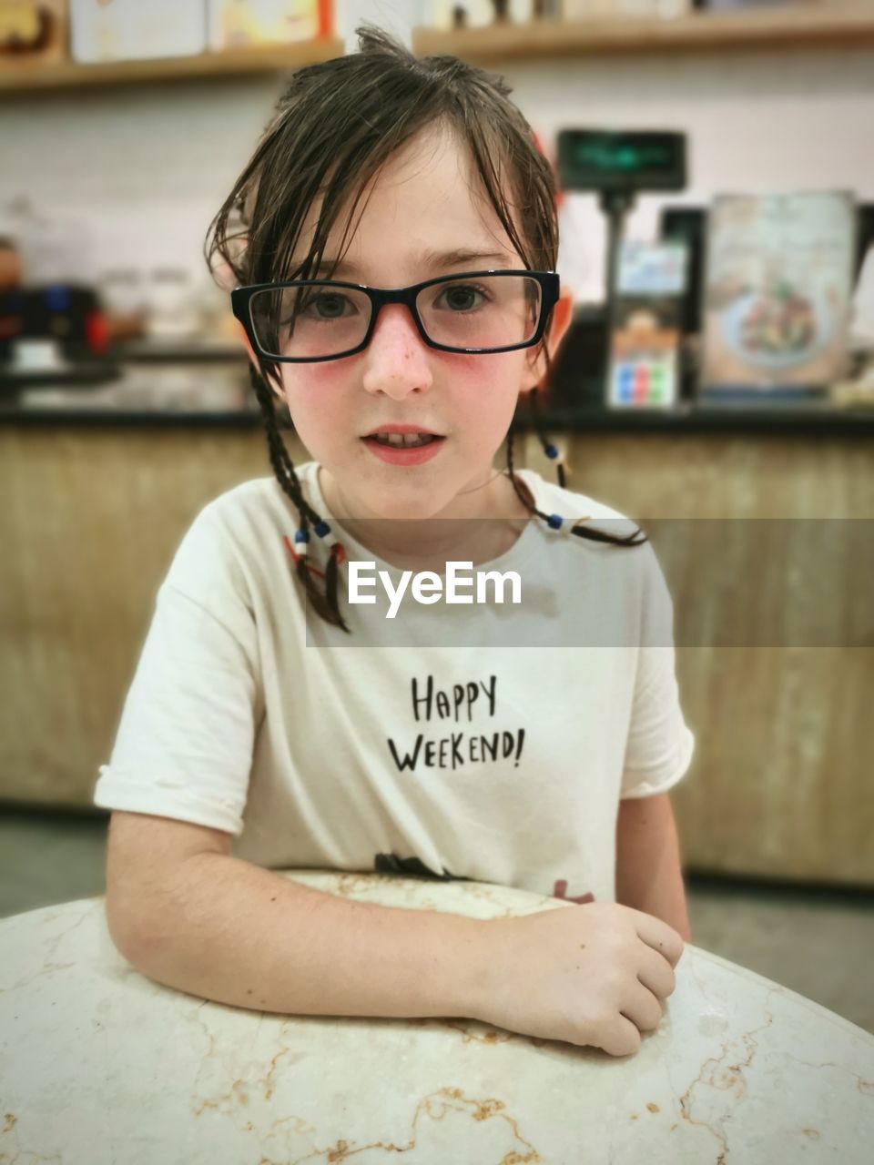 Portrait of girl wearing eyeglasses leaning on a table