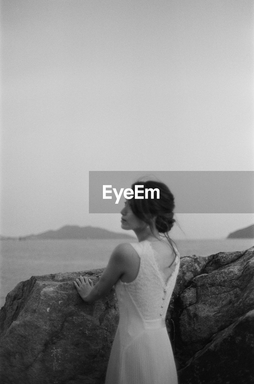 Bride standing at beach against sky