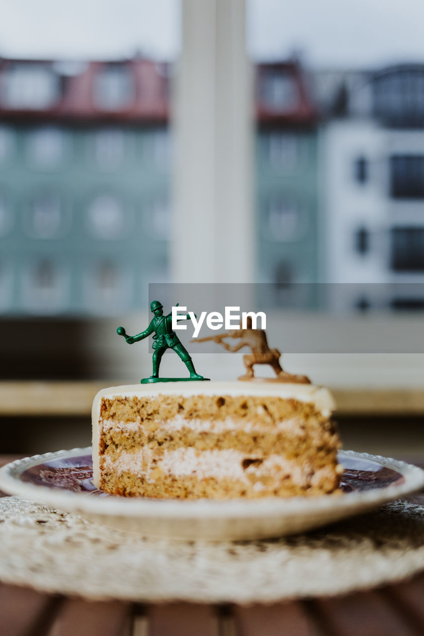 Two toy soldiers fighting on the top of piece of cake about having a dessert or not - close up cake