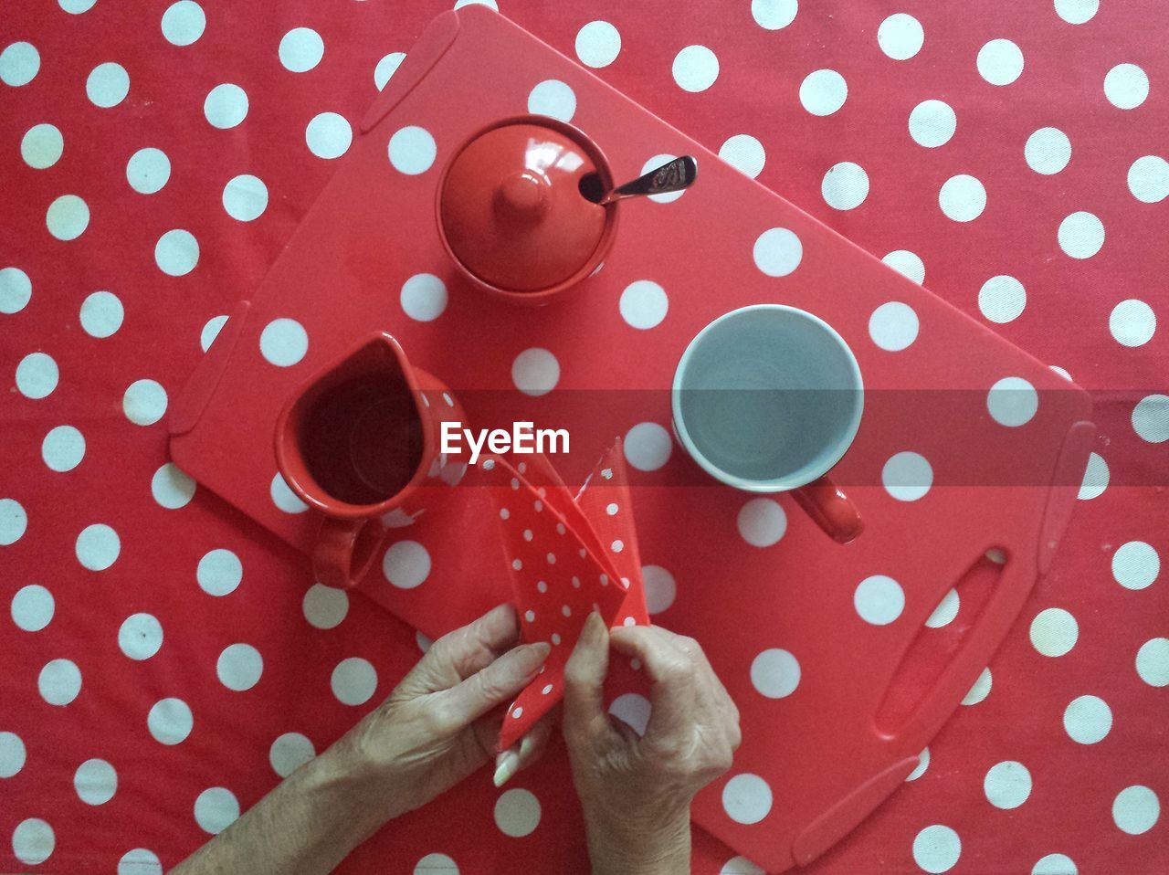 Cropped image of hand holding napkin by coffee cup and container on table