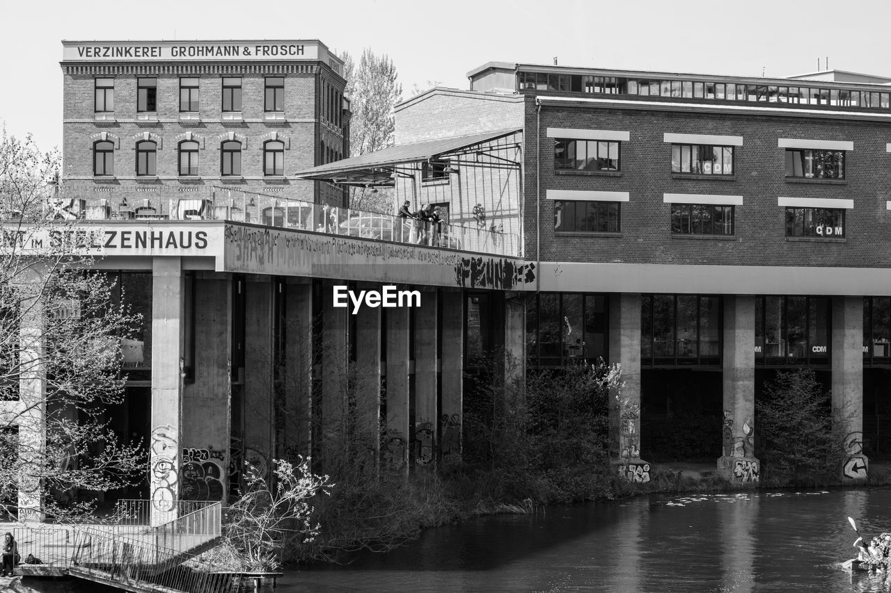 architecture, built structure, building exterior, water, black and white, monochrome photography, monochrome, urban area, nature, waterway, building, day, house, no people, bridge, river, tree, plant, outdoors, sky, text