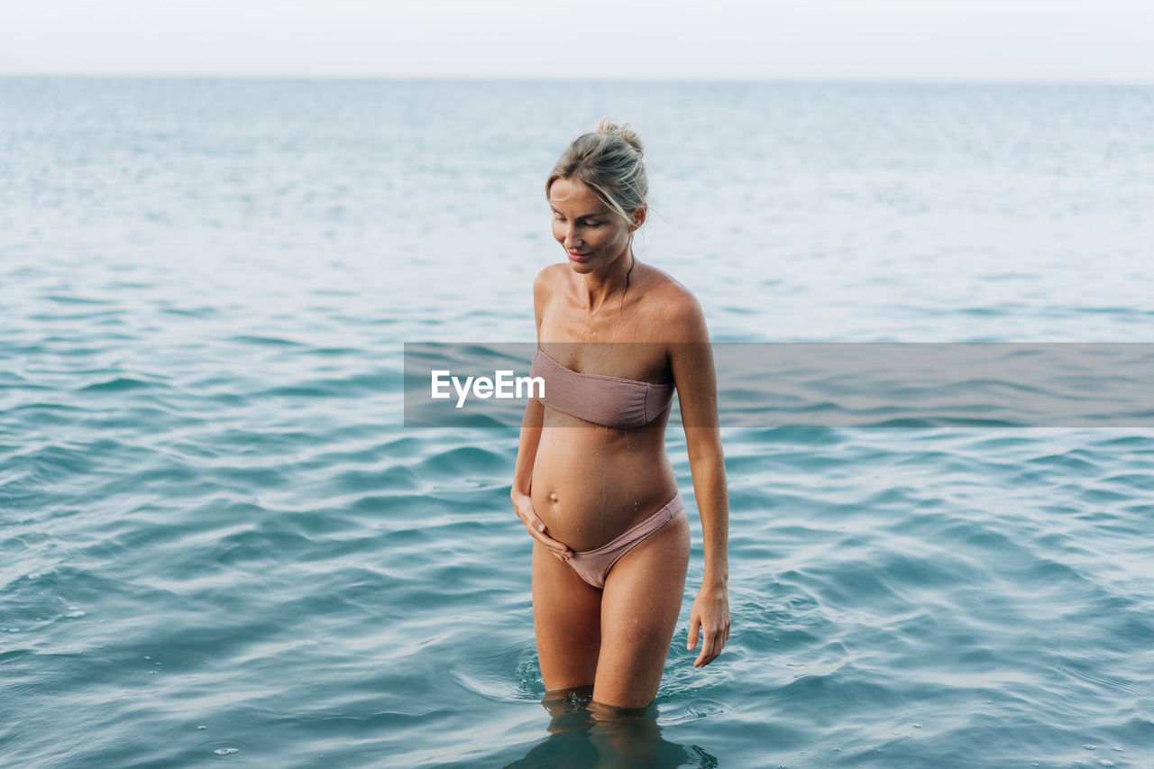 A pregnant woman swims in the sea and comes ashore.