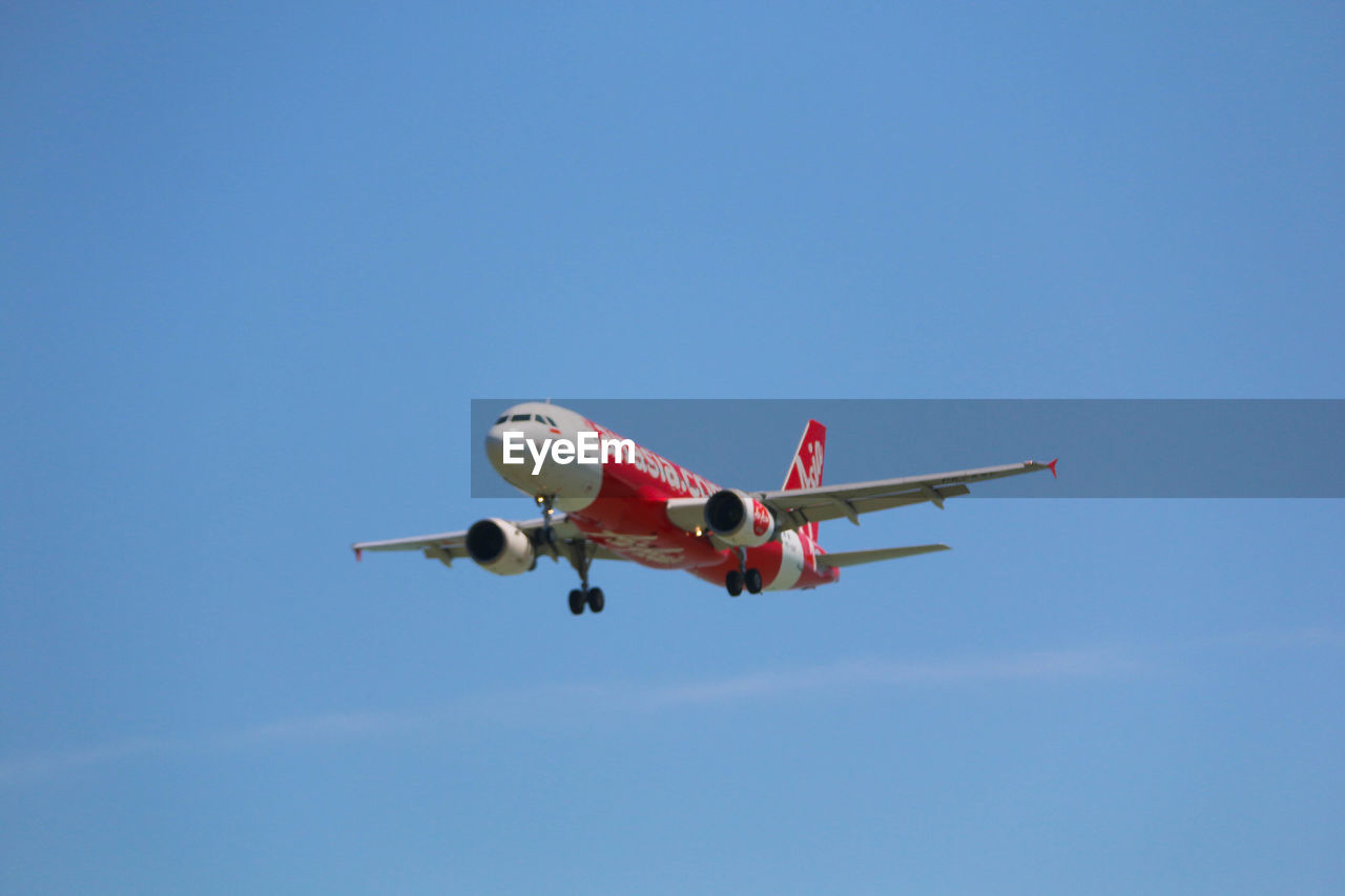 LOW ANGLE VIEW OF AIRPLANE IN FLIGHT AGAINST CLEAR BLUE SKY
