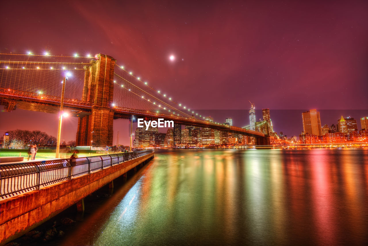 Illuminated bridge over river at night