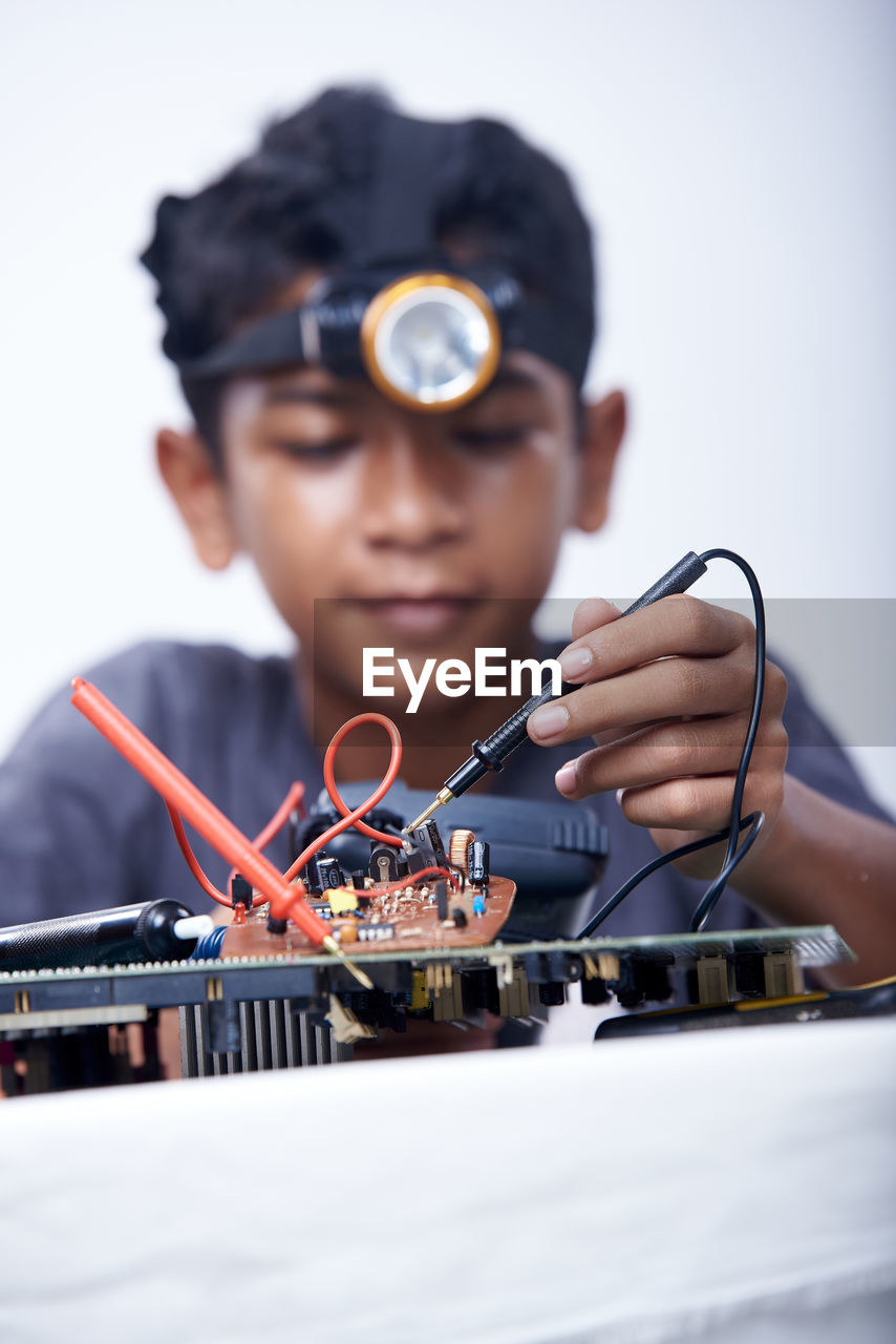 Young schoolboy learning electronic circuit board. detail focus on board component