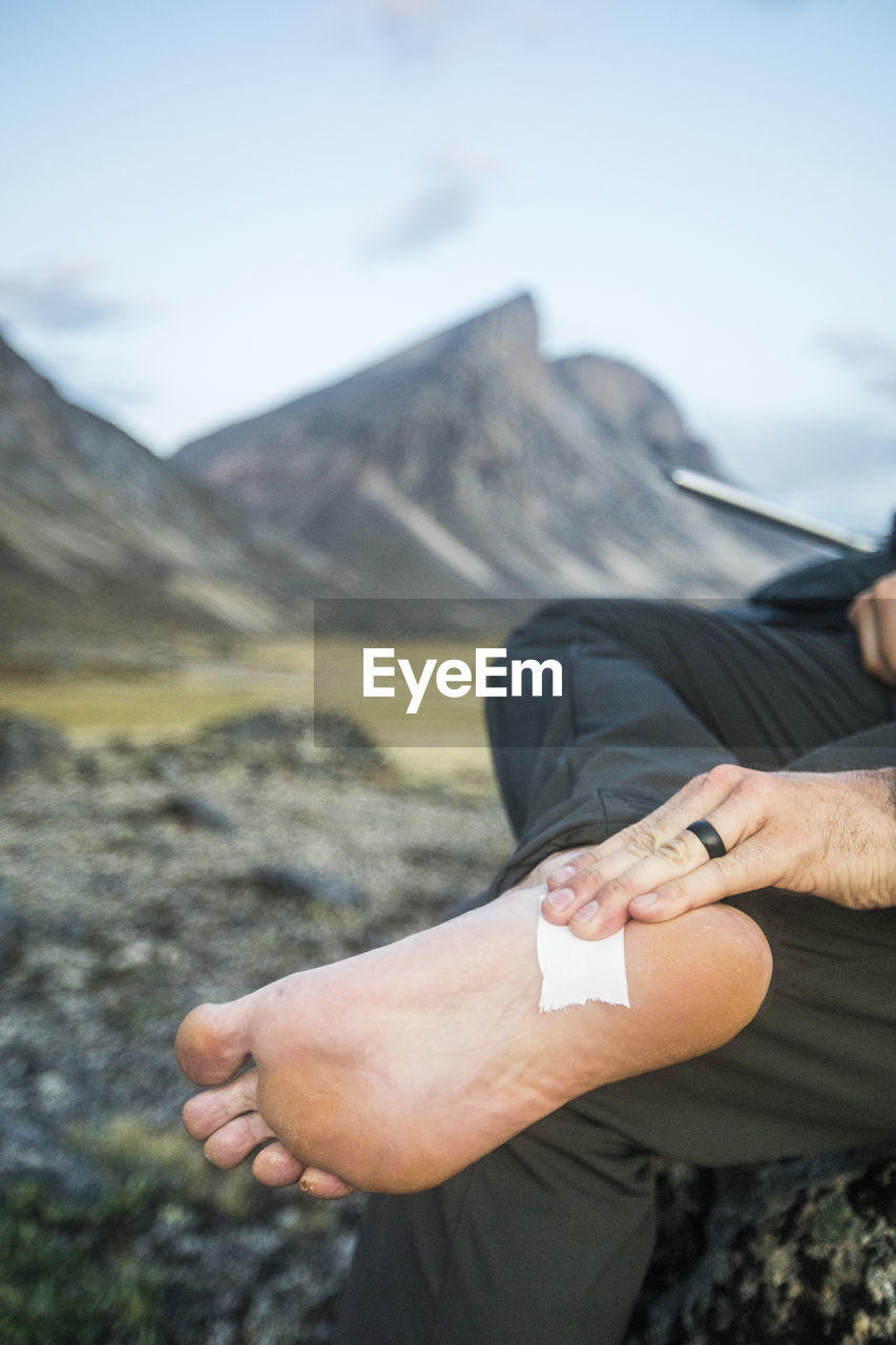 Hiker tapes foot where blister was forming on foot.