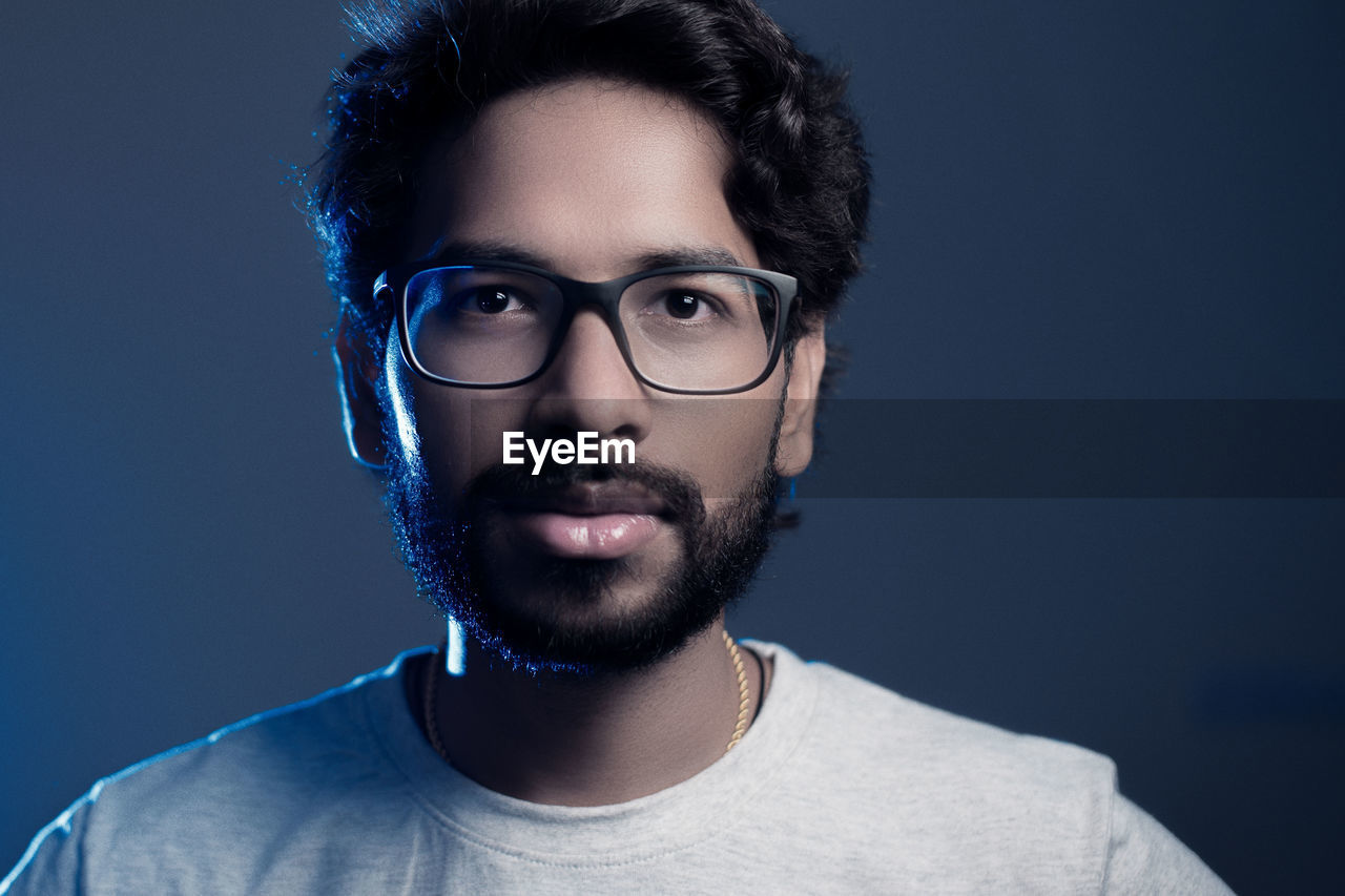 Portrait of bearded man in eyeglasses against gray background