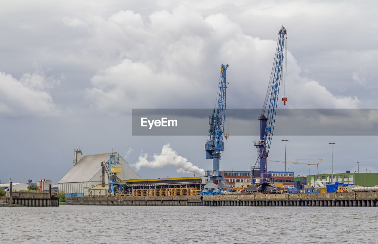 CRANES BY PIER AGAINST SKY