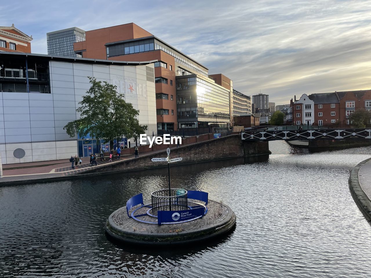 Buildings by canal against sky in city