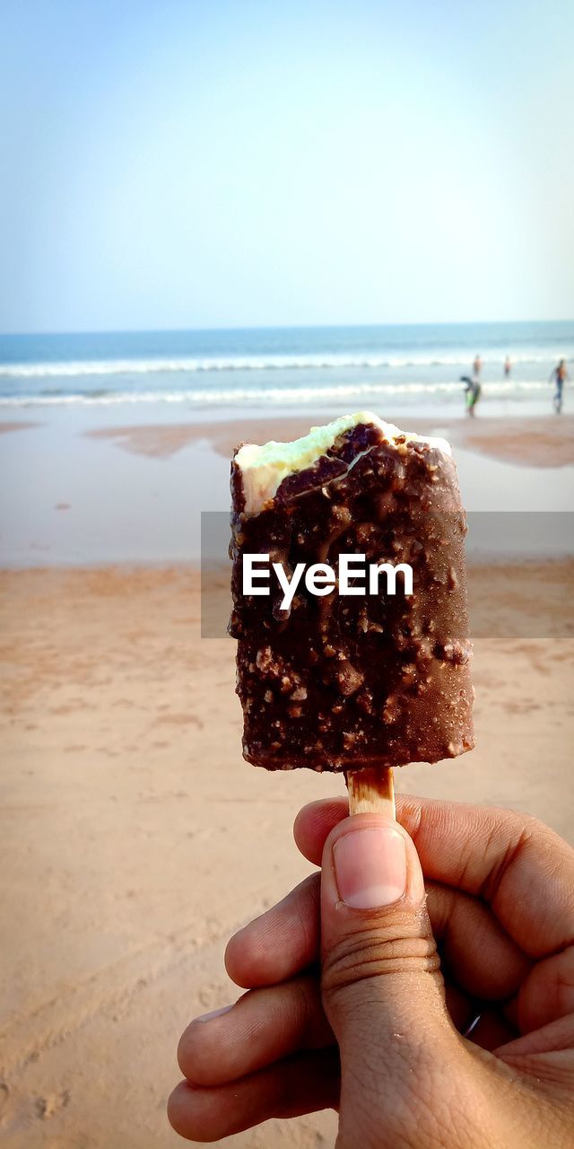 Person holding ice cream on beach