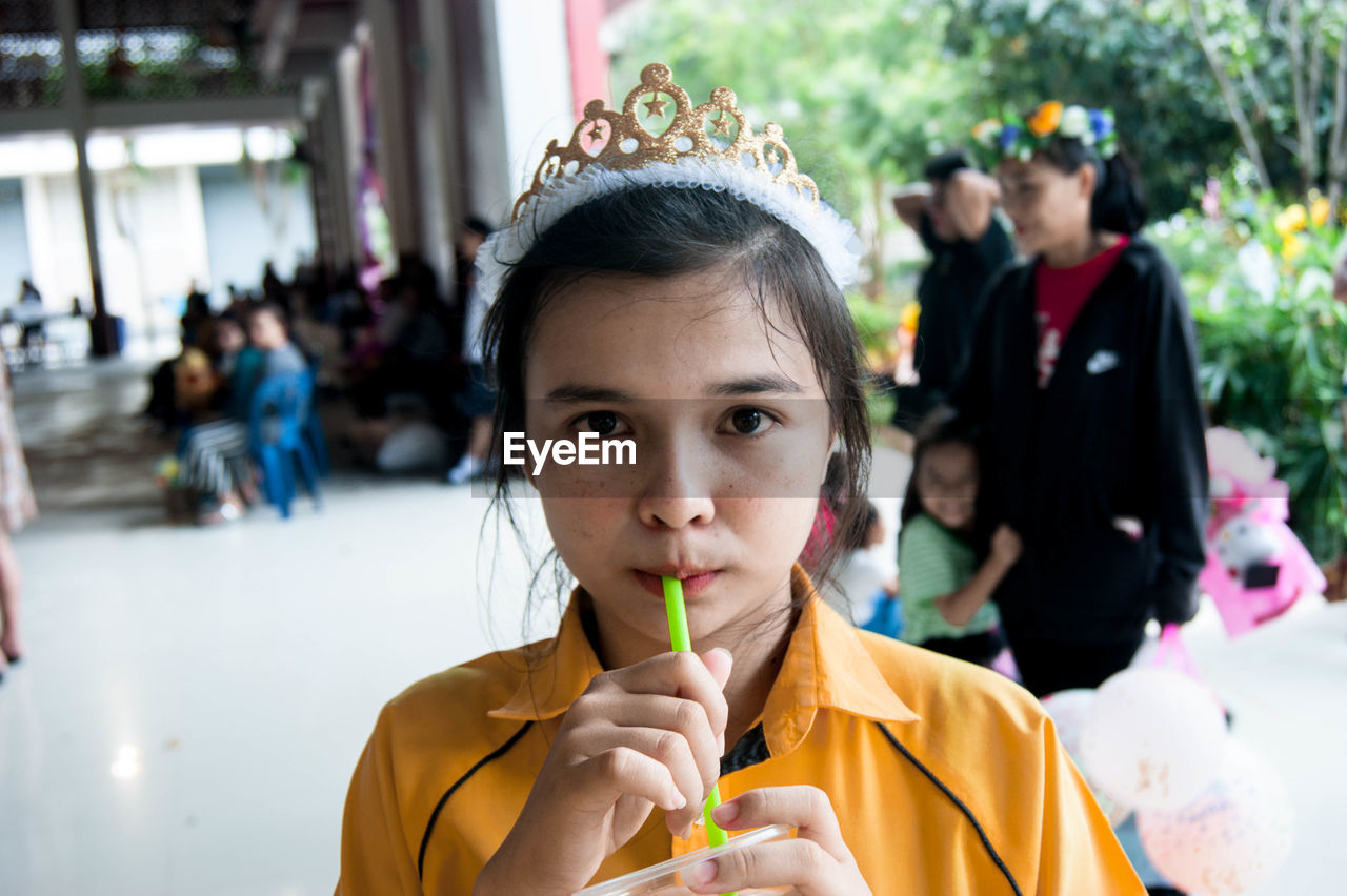 Portrait of girl wearing tiara drinking drink during party