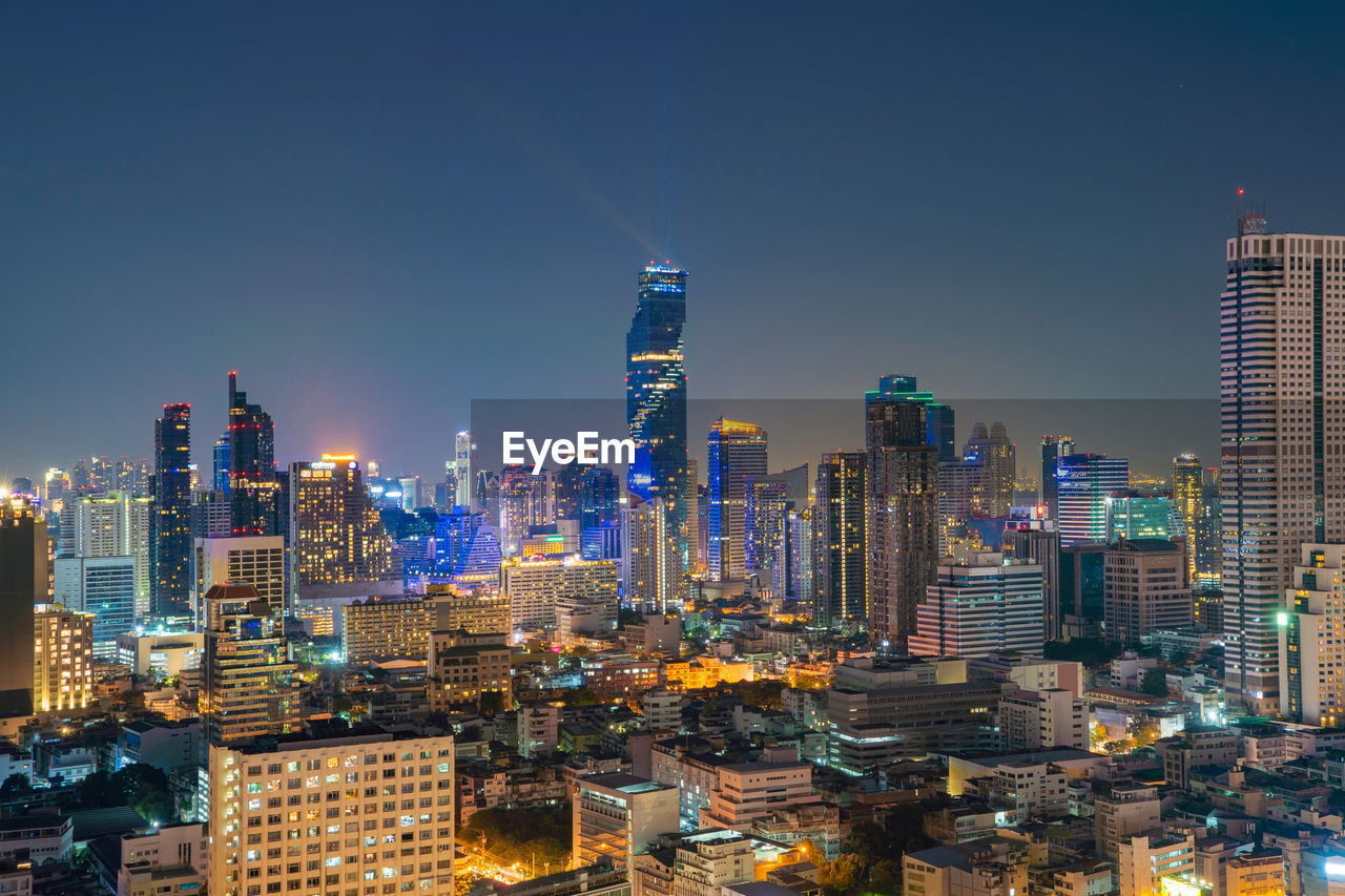 AERIAL VIEW OF ILLUMINATED BUILDINGS IN CITY AGAINST SKY